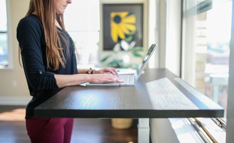 woman in black shirt sitting at the table using macbook