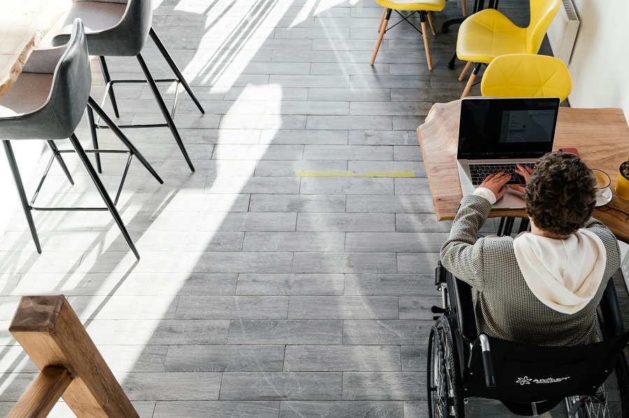 A man sitting on a wheelchair in front of his laptop