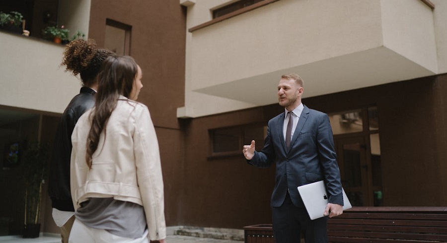  two women and a real estate agent in front of a house