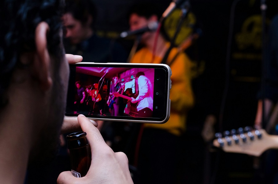 Person holding a black phone and filming people