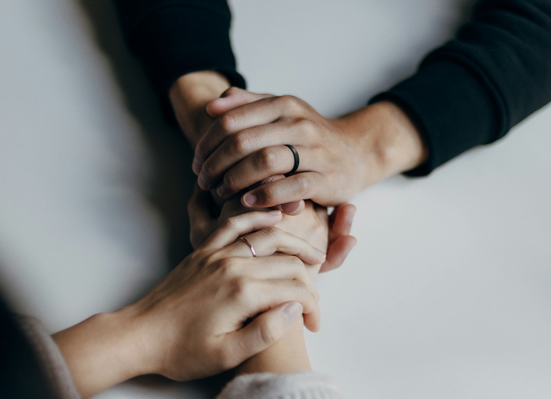 person in black long sleeve shirt holding womans hands 