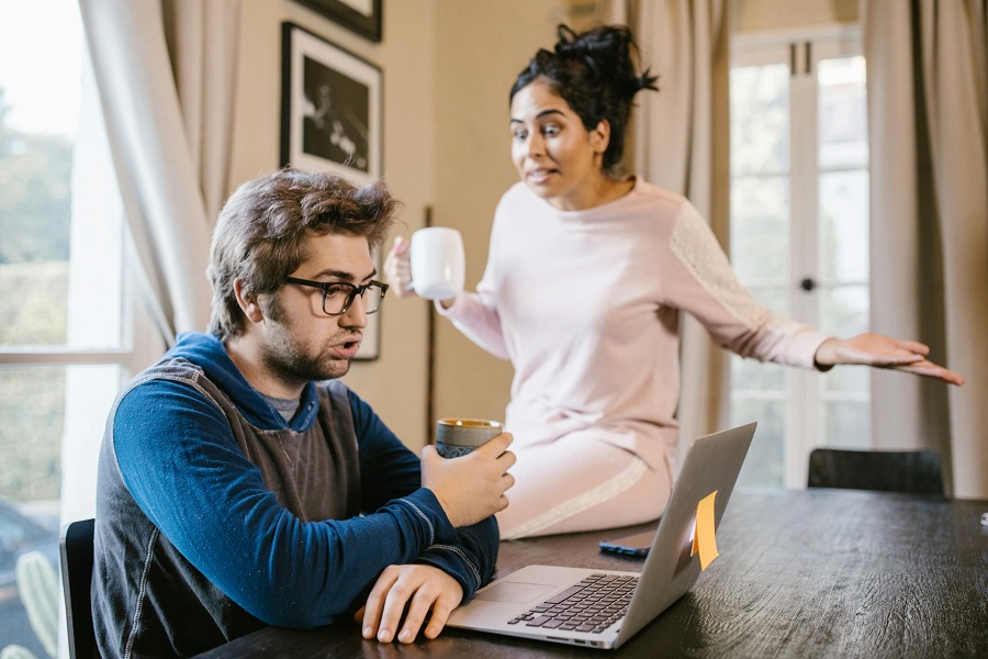 a man sitting in front of a laptop beside an upset woman