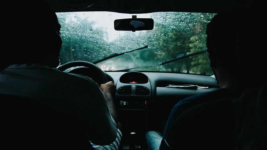 Two men in a moving car under the rain